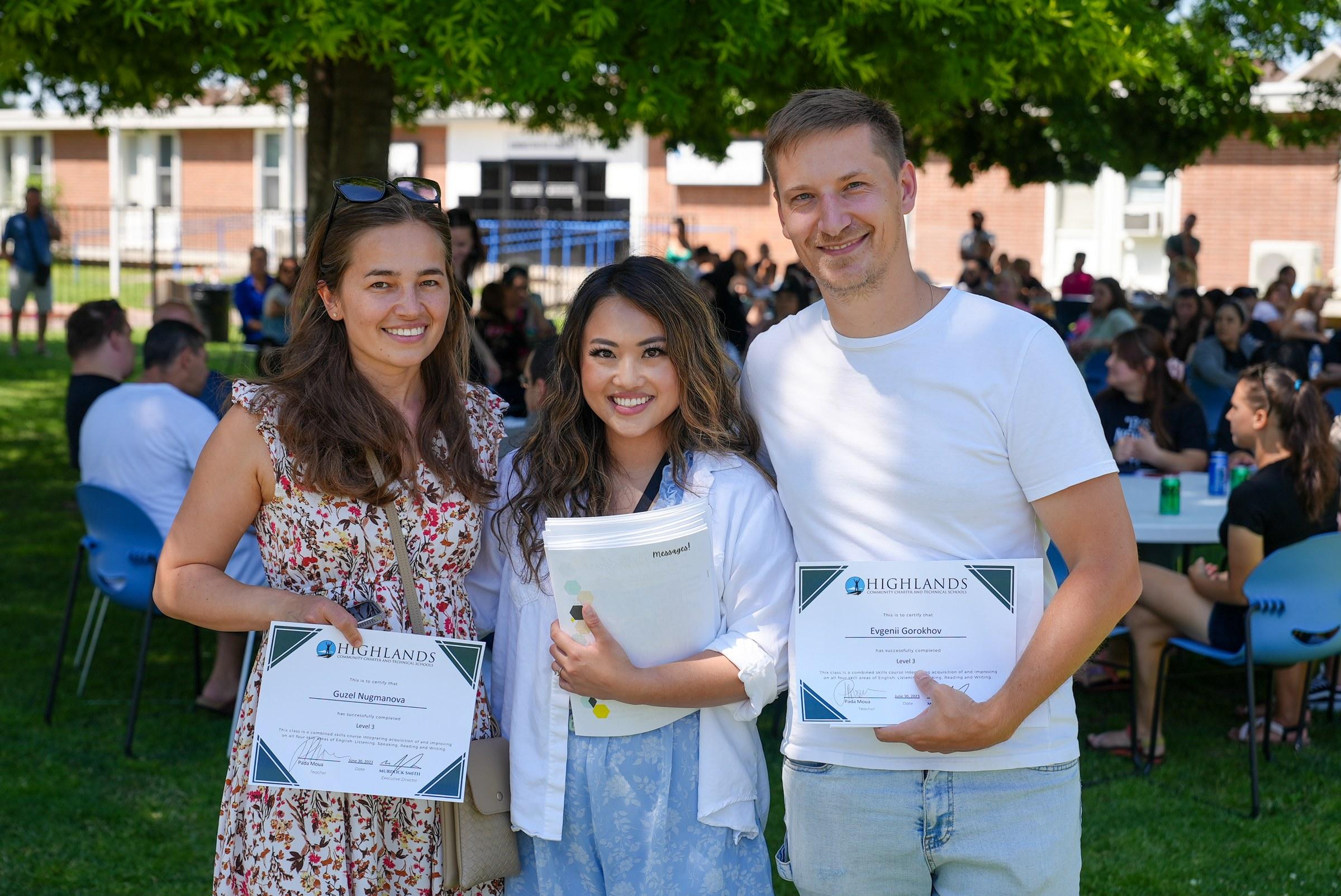 Three HCCTS community members smiling outdoors, each holding a Highlands completion certificate after finishing an English Language class.